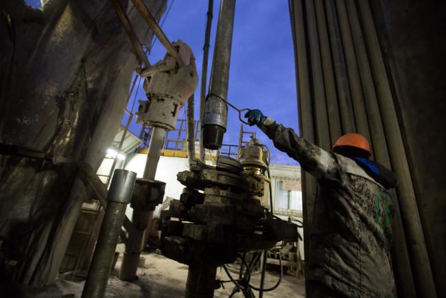 © Bloomberg. A worker uses a hook to position a drill bit on a drill rig during oil drilling operations by Targin JSC, a unit of Sistema PJSFC, in an oilfield operated by Bashneft PAO near Ufa, Russia.