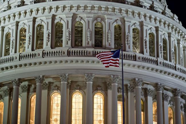 © Bloomberg. An American flag flies at the U.S. Capitol before sunrise in Washington, D.C., U.S., on Friday, Oct. 20, 2017. President Donald Trump's top legislative priority took a major step forward as the Senate narrowly approved a budget vehicle for tax cuts -- but sharp divides over an array of non-binding amendments revealed the towering challenge he faces from here.