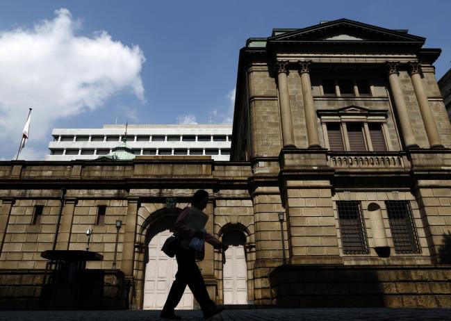© Bloomberg. A woman walks past the Bank of Japan headquarters in Tokyo, Japan, on Monday, Sept. 28, 2015. 