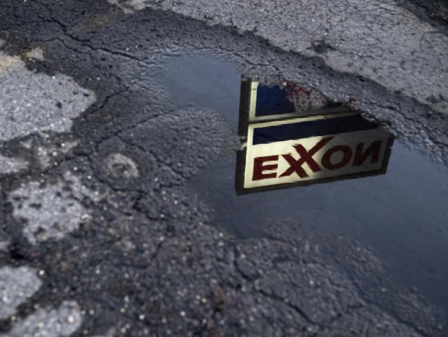 © Bloomberg. Exxon Mobil Corp. signage is reflected in a puddle at a gas station in Nashport, Ohio, U.S., on Friday, Jan. 26, 2018. 