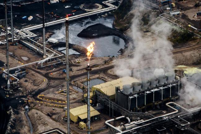 © Bloomberg. Flames shoot from a flare at the Suncor Energy Inc. Millennium upgrader plant in this aerial photograph taken above the Athabasca oil sands near Fort McMurray, Alberta, Canada, on Monday, Sept. 10, 2018. While the upfront spending on a mine tends to be costlier than developing more common oil-sands wells, their decades-long lifespans can make them lucrative in the future for companies willing to wait. Photographer: Ben Nelms/Bloomberg
