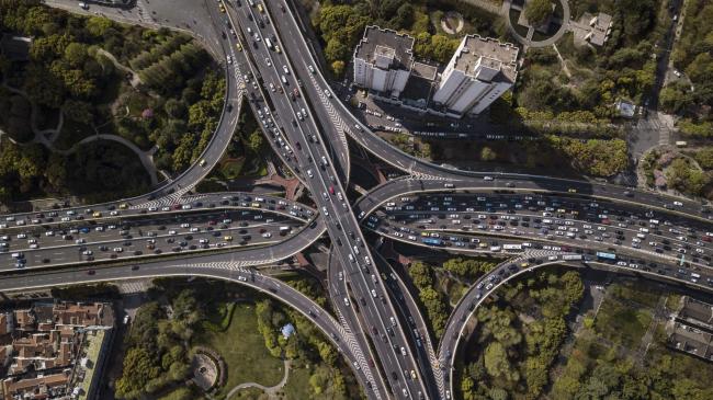 © Bloomberg. Vehicles travel along highways in this aerial photograph taken above Shanghai, China, on Monday, April 2, 2018. China's sprawling local government financing system needs 