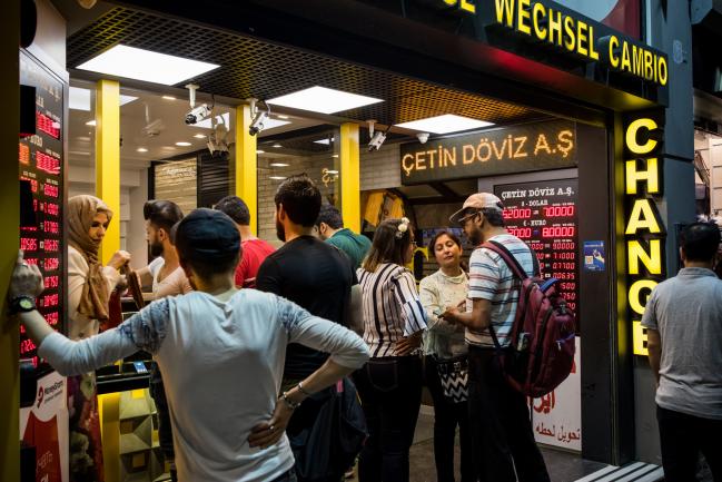 © Bloomberg. Tourists change money at a foreign currency bureau in Istanbul, Turkey, on Monday, Aug. 13, 2018. President Recep Tayyip Erdogan vowed to boycott iPhones in a demonstration of defiance as the U.S. held firm to its demand that Turkey release an evangelical pastor and Turkish executives called for action to bolster the lira. Photographer: Nicole Tung/Bloomberg