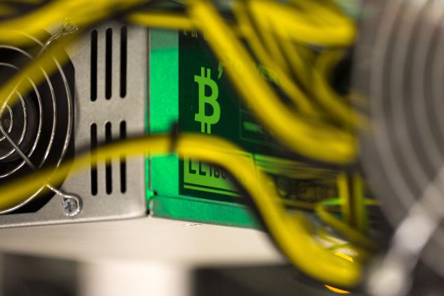 © Bloomberg. A bitcoin logo sits on a LL 1800W power unit supplying cryptocurrency mining machines at the SberBit mining 'hotel' in Moscow, Russia, on Saturday, Dec. 9, 2017. Futures on the world’s most popular cryptocurrency surged as much as 26 percent in their debut session on Cboe Global Markets Inc.'s exchange, triggering two temporary trading halts designed to calm the market.