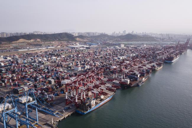 © Bloomberg. Cargo ships are moored under cranes as shipping containers stand at the Qingdao Qianwan Container Terminal in this aerial photograph taken in Qingdao, China, on Monday, May 7, 2018. Photographer: Qilai Shen/Bloomberg