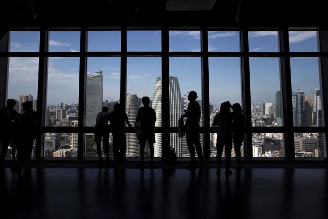 © Bloomberg. Visitors are silhouetted as they look out of windows at an observatory in the central business district of Tokyo, Japan, on Wednesday, June 27, 2018. The Bank of Japan's (BOJ) Tankan quarterly business survey for June, scheduled to be released on July 2, is likely to show concerns about U.S. tariffs putting a dent in business sentiment. Photographer: Tomohiro Ohsumi/Bloomberg