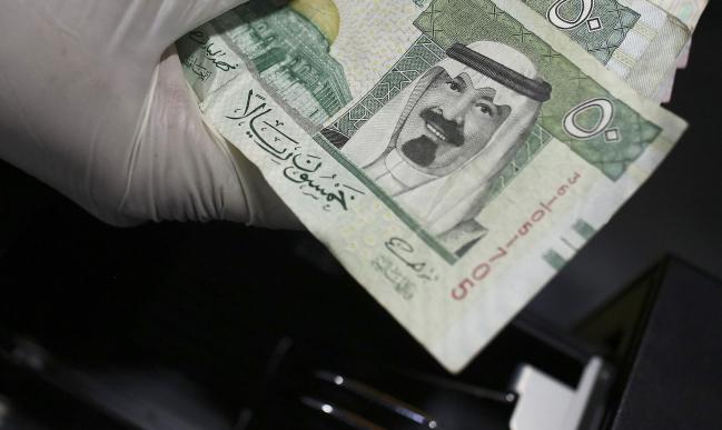 &copy Bloomberg. An employee counts a handful of Riyal banknotes from the cash till of a mobile burger van located on the side of a highway in Riyadh, Saudi Arabia, on Tuesday, Nov. 29, 2016. Saudi Arabia is working to reduce the the Middle Easts biggest economys reliance on oil, which provides three-quarters of government revenue, as part of a plan for the biggest economic shakeup since the countrys founding.