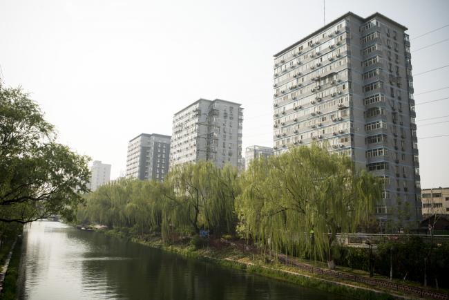 © Bloomberg. Residential buildings and willow trees stand along a canal in the Yonghegong area of Beijing, China, on Monday, April 16, 2018. New home prices in Beijing and Shanghai have jump more than 25 percent over the last two years. Photographer: Giulia Marchi/Bloomberg