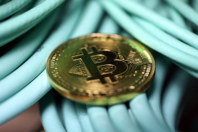 © Bloomberg. A bitcoin sits on coaxial cables inside a communications room at an office in this arranged photograph in London, U.K., on Tuesday, Sept. 5, 2017. Bitcoin steadied after its biggest drop since June as investors and speculators reappraised the outlook for initial coin offerings.