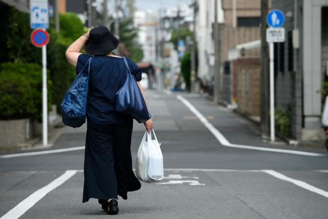 © Bloomberg. A shopper carries shopping bags as she walks along a road in Tokyo, Japan, on Friday, Aug. 3, 2018. Rising prices generally make consumers defensive about spending, so stronger wage gains are critical for households to accept price increases, Japan's central bank said in an analysis of wages and prices on July 31. Photographer: Akio Kon/Bloomberg