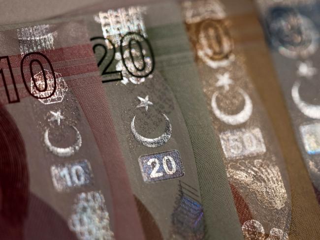 © Bloomberg. Star and Cresent symbols sit on an assortment of Turkish Lira banknotes in this arranged photograph in London, U.K., on Wednesday, Aug. 15, 2018. Turkey took its boldest steps yet to try to ward off a financial crisis by making it harder for traders to bet against the battered lira and easing rules on restructuring troubled loans that have already topped $20 billion. Photographer: Chris Ratcliffe/Bloomberg