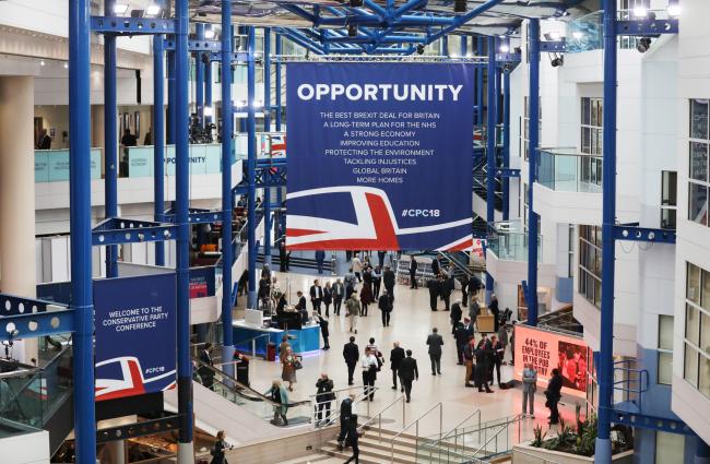 © Bloomberg. Delegates gather under a large banner reading 'Opportunity' during the Conservative Party annual conference in Birmingham, U.K., on Sunday, Sept. 30, 2018. Theresa May is battling to assert her authority as U.K. prime minister after a disastrous start to her party’s annual conference threatened to explode into a full-blown leadership crisis. Photographer: Chris Ratcliffe/Bloomberg