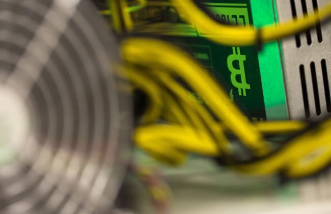 © Bloomberg. A bitcoin logo sits on a LL 1800W power unit supplying cryptocurrency mining machines at the SberBit mining 'hotel' in Moscow, Russia, on Saturday, Dec. 9, 2017. Futureson the worlds most popular cryptocurrency surged as much as 26 percent in their debut session on Cboe Global Markets Inc.'s exchange, triggering two temporary trading halts designed to calm the market.