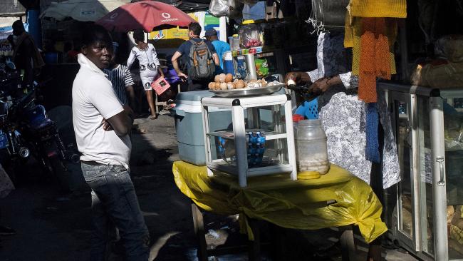 © Bloomberg. Customers walk through a market in Accra, Ghana.