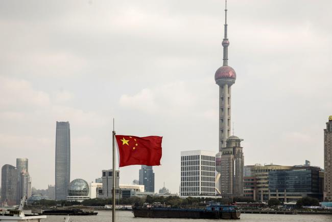 © Bloomberg. A Chinese national flag flies as skyscrapers of the Pudong Lujiazui Financial District stand across the Huangpu River in Shanghai, China, on Friday, Dec. 28, 2018. China announced plans to rein in the expansion of lending by the nation's regional banks to areas beyond their home bases, the latest step policy makers have taken to defend against financial risk in the world's second-biggest economy. Photographer: Qilai Shen/Bloomberg