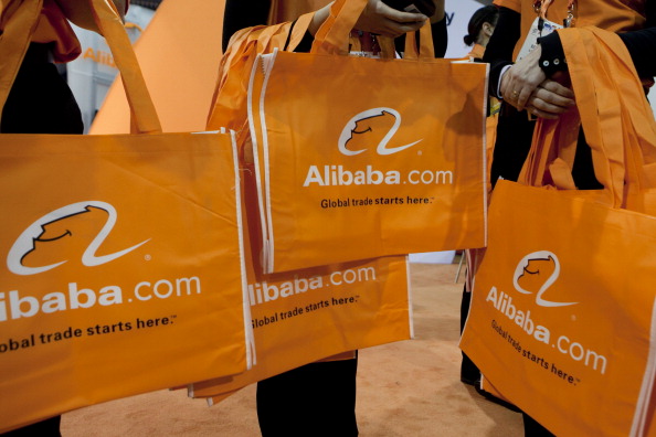 © Bloomberg. Alibaba.com Ltd. bags are distributed at the 2012 International Consumer Electronics Show (CES) in Las Vegas, Nevada, U.S., on Friday, Jan. 13, 2012. Alibaba Group Holding Ltd. is considering reducing the size of a loan for a potential Yahoo! Inc. acquisition to around $3 billion from the original target of $4 billion in order to use its cash instead. Photographer: Bloomberg/Bloomberg