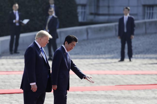 © Bloomberg. Shinzo Abe, Japan's prime minister, right, gestures to U.S. President Donald Trump, while observing an honor guard at Akasaka Palace in Tokyo, Japan, on Monday, Nov. 6, 2017. Trump is on the first stop of a five-nation swing through Asia where he plans to push his message of fair trade and freedom in the region backed by a strong U.S. military presence. 