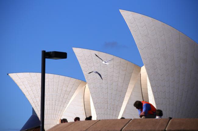 © Bloomberg. Seagulls fly past the Sydney Opera House in Sydney, Australia, on Wednesday, May 15, 2019. Australia's economy has been weighed down by a retrenchment in household spending as property prices slump and slash personal wealth. An election Saturday is likely to see the opposition Labor party win power and lift spending further. Photographer: David Gray/Bloomberg
