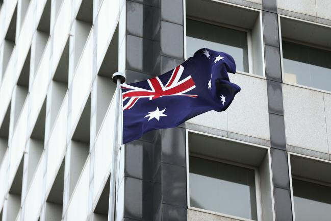 © Bloomberg. The Australian flag flies outside the Reserve Bank of Australia (RBA) headquarters in Sydney, Australia, on Monday, Dec. 4, 2017. Australia's central bank is on track for its longest stretch of unchanged interest rates as it bets a tightening job market will begin to put upward pressure on wages -- at some stage. 