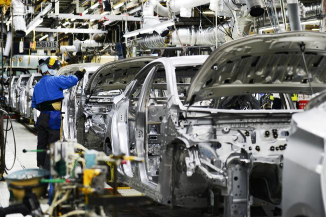 © Bloomberg. A worker stands next to vehicles moving along a conveyor on the Prius hybrid and Priyus plug-in hybrid vehicle (PHV) production line of the Toyota Motor Corp. Tsutsumi plant in Toyota City, Aichi, Japan, on Saturday, Dec. 8, 2017. This year marks the 20th anniversary of the Prius, the world's first mass-produced hybrid passenger vehicle.