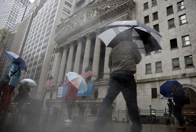 © Bloomberg. Pedestrians carry umbrellas while walking past the New York Stock Exchange (NYSE) in New York, U.S., on Friday, May 6, 2016. U.S. stocks retreated a fourth day, with the S&P 500 poised for its first back-to-back weekly drop since February, after the smallest jobs gain in seven months raised doubts about the strength of the worlds largest economy.