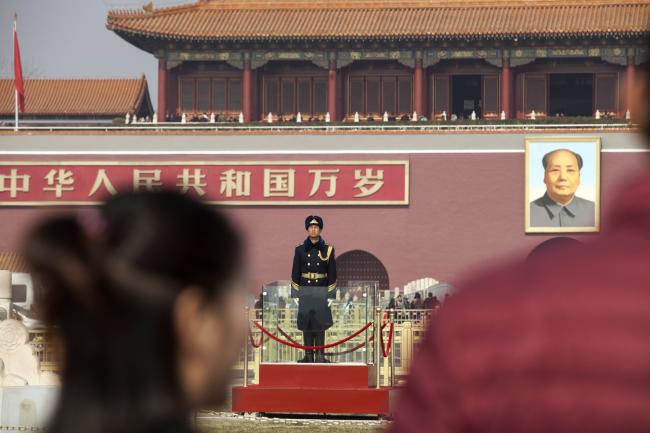 © Bloomberg. A member of the Chinese People's Liberation Army stands guard in front of a portrait of former Chinese leader Mao Zedong at Tiananmen Square in Beijing, China, on Monday, Feb. 26, 2018. 