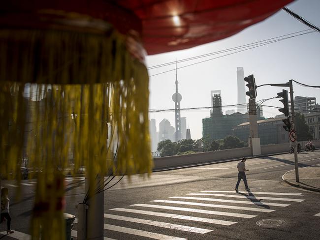 © Bloomberg. A pedestrian crosses a road as buildings of Pudong's Lujiazui financial district stand in the distance in Shanghai, China, on Friday, Oct. 2, 2015. China's consumer inflation moderated and factory gate deflation extended a record stretch of declines, signaling the People's Bank of China still has room to ease monetary policy further to support a slowing economy. Photographer: Bloomberg/Bloomberg