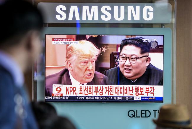 © Bloomberg. People watch a television screen broadcasting a news report, featuring images of U.S. President Donald Trump, left, and North Korean leader Kim Jong Un, right, at Seoul Station in Seoul, South Korea, on Friday, May 25, 2018. A historic summit between Trump and Kim -- abruptly agreed to with little plan for how events would unfold -- collapsed as the leaders talked past each other on their goals, phone calls weren’t returned and rhetoric turned from hopeful to sour. Photographer: Jean Chung/Bloomberg