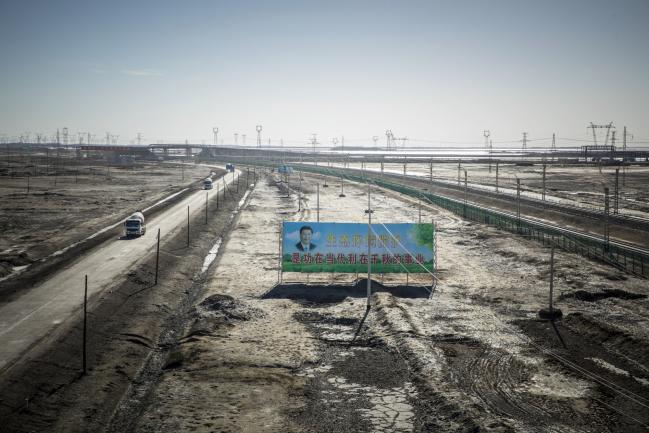 © Bloomberg. A billboard featuring Chinese President Xi Jinping and promoting environmental protection stands among power lines carrying electricity from the Golmud Solar Park on the outskirts of Golmud, Qinghai province, China, on Wednesday, July 25, 2018. Amid rising fears about a trade war, China's policy makers have unveiled measures to boost infrastructure construction and credit to smaller firms, as well as tax cuts. Photographer: Qilai Shen/Bloomberg