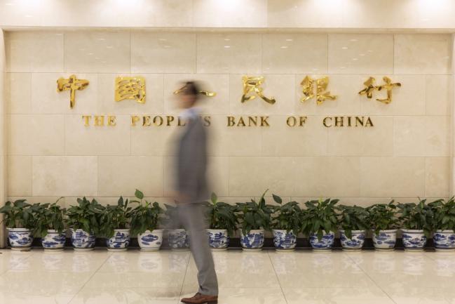 © Bloomberg. A man walks past signage at the lobby of the People's Bank of China (PBOC) headquarters in Beijing, China, on Friday, June 7, 2019. China's central bank governor said there's 