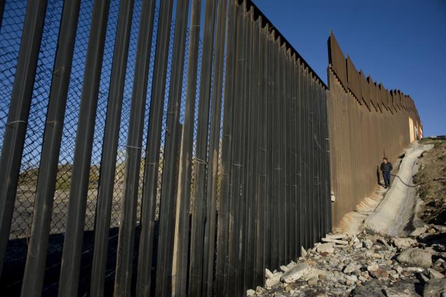 © Bloomberg. A person walks along a section of the border wall that separates the U.S. and Mexico in Tijuana, Mexico, on Thursday, Jan. 26, 2017. U.S. President Donald Trump signed a pair of orders to set in motion the construction of a 