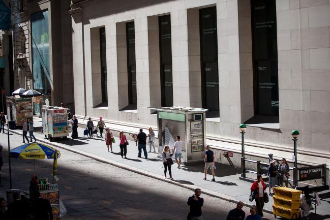 © Bloomberg. Pedestrians walk along Wall Street near the New York Stock Exchange (NYSE) in New York, U.S., on Friday, Sept. 8, 2017. The dollar fell to the weakest in more than two years, while stocks were mixed as natural disasters damped expectations for another U.S. rate increase this year.