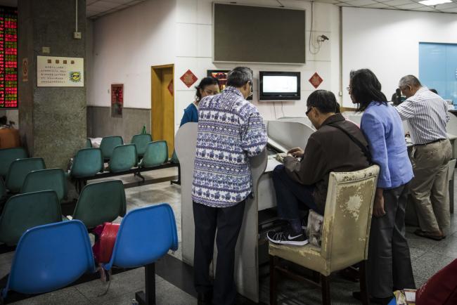 © Bloomberg. Investors stand at trading terminals at a securities brokerage in Shanghai, China, on Friday, Oct. 13, 2017. A number of economic indicators show 