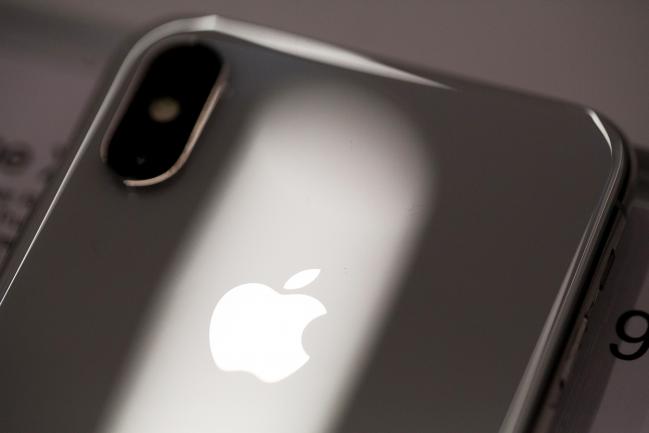 © Bloomberg. A logo sits on the case of an iPhone X smartphone on the first day of sale Customers queue at a re:Store Apple Inc. retailer in Moscow, Russia, on Friday, Nov. 3, 2017. Supported by resurgent iPad and Mac sales, the 10-year anniversary iPhone will help push revenue to a record high of $84 billion to $87 billion in the quarter ending in late December, Apple said in a statement. Photographer: Andrey Rudakov/Bloomberg