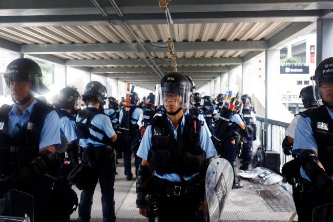© Bloomberg. Riot police stand guard on a bridge near the Legislative Council building on June 13. Photographer: Eduardo Leal/Bloomberg