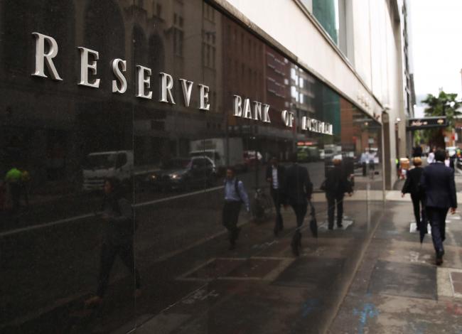 © Bloomberg. Pedestrians walk past the Reserve Bank of Australia (RBA) headquarters in Sydney, Australia, on Monday, Dec. 4, 2017. Australia's central bank is on track for its longest stretch of unchanged interest rates as it bets a tightening job market will begin to put upward pressure on wages -- at some stage.