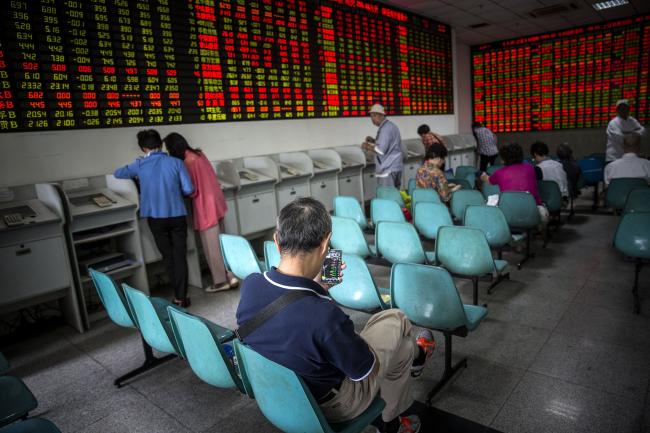 © Bloomberg. A man looks at stock quotes on his mobile phone at a securities exchange house in Shanghai, China. Photographer: Qilai Shen