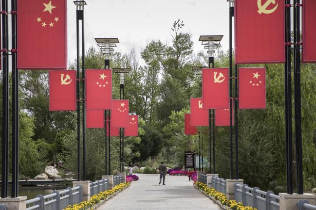 © Bloomberg. The Chinese national flag and the Chinese Communist Party flag hang on display at a park commemorating General Mu Shengzhong, also known as the father of the Qinghai-Tibet Highway, in Golmud, Qinghai province, China, on Sunday, July 22, 2018. Amid rising fears about a trade war, China's policy makers have unveiled measures to boost infrastructure construction and credit to smaller firms, as well as tax cuts. 