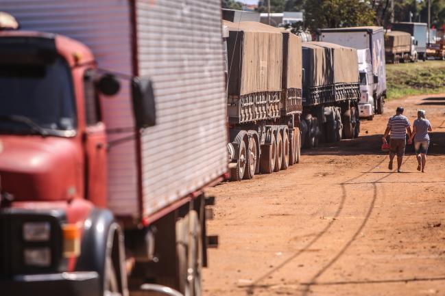 © Bloomberg. People walk past trucks parked on BR 040 highway in Luziania, Brazil, on May 23. Photographer: Andre Coelho/Bloomberg