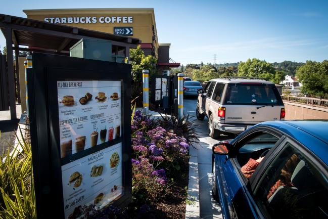 © Bloomberg. Customers wait in line to make a purchase at the drive-thru of a Starbucks Corp. coffee shop in Pinole, California. Photographer: David Paul Morris/Bloomberg