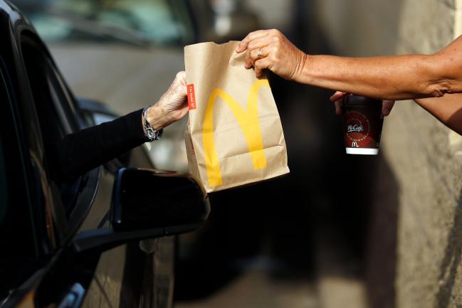 © Bloomberg. A worker passes a bag of food to a customer at the drive-thru window at a McDonald's fast food restaurant in White House, Tennessee, U.S., on Wednesday, Jan. 18, 2017. McDonald's shares fell as much as 2 percent to $119.82 on Monday after the results were posted.