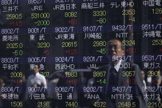 © Bloomberg. A pedestrian is reflected in an electronic stock board outside a securities firm in Tokyo, Japan, on Wednesday, Oct. 18, 2017.