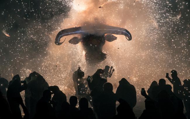 © Bloomberg. Attendees use mobile devices to take photographs while sparks fly from a 