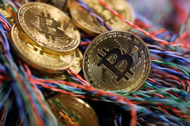 © Bloomberg. Bitcoins sit among twisted copper wiring inside a communications room at an office in this arranged photograph in London, U.K., on Tuesday, Sept. 5, 2017. Bitcoin steadied after its biggest drop since June as investors and speculators reappraised the outlook for initial coin offerings.