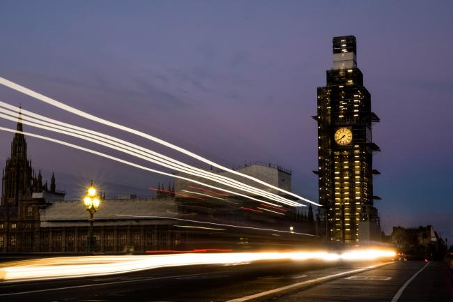 © Bloomberg. A bus casts light trails as it passes the Houses of Parliament and Elizabeth Tower, also known as 'Big Ben', in London in London, U.K. 