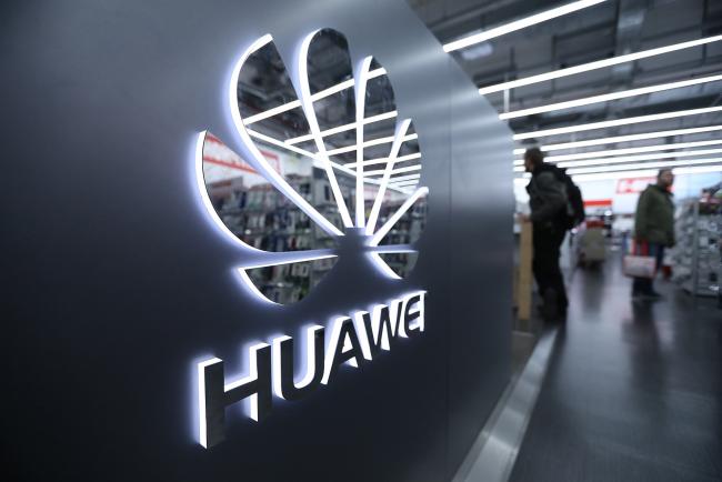 © Bloomberg. A Huawei Technologies Co. logo sits on display as customers browse inside a Media Markt electronic goods store, operated by Ceconomy AG, in Berlin, Germany. 