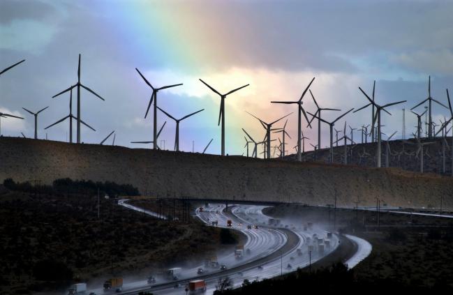 © Bloomberg. PALM SPRINGS, CA - DECEMBER 17: A rainbow forms behind giant windmills near rain-soaked Interstate 10 as an El Nino-influenced storm passes over the state on December 17, 2002 near Palm Springs, California. Because of consistantly high winds, thousands of giant windmills have sprouted in the area to create wind-powered electricity. (Photo by David McNew/Getty Images) 