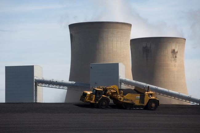 © Bloomberg. Vehicles move coal ash as cooling towers stand in the Drax Group Plc's power station near Selby, U.K., on Wednesday, May 4, 2016.  Photographer: Simon Dawson/ Bloomberg