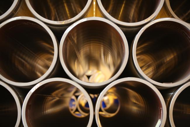 © Bloomberg. Large diameter steel pipes sit in a storage area. 