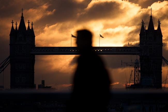 © Bloomberg. A commuter walks across London Bridge against a backdrop of Tower Bridge during sunrise in London, U.K., on Friday, Oct. 21, 2016. London, the city of almost 9 million people is the 